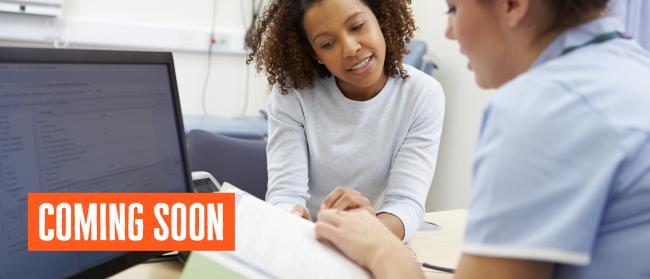 Two people at a healthcare appointment looking at a document, with 'coming soon' written in the bottom left corner